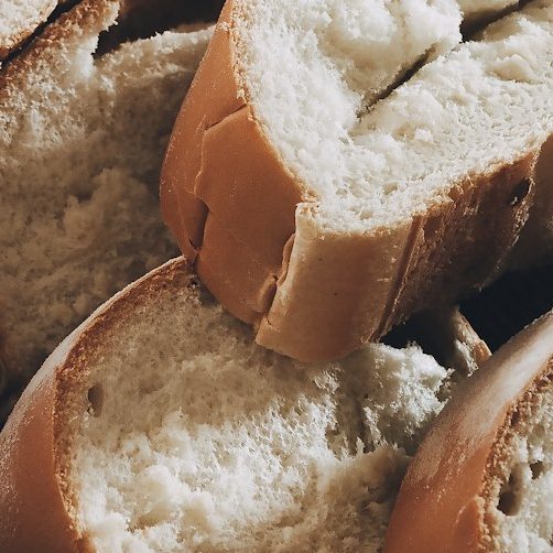 Aufgeschnittenes Brot mit einer hellbraunen Kruste und weichem, weißem Innenleben.